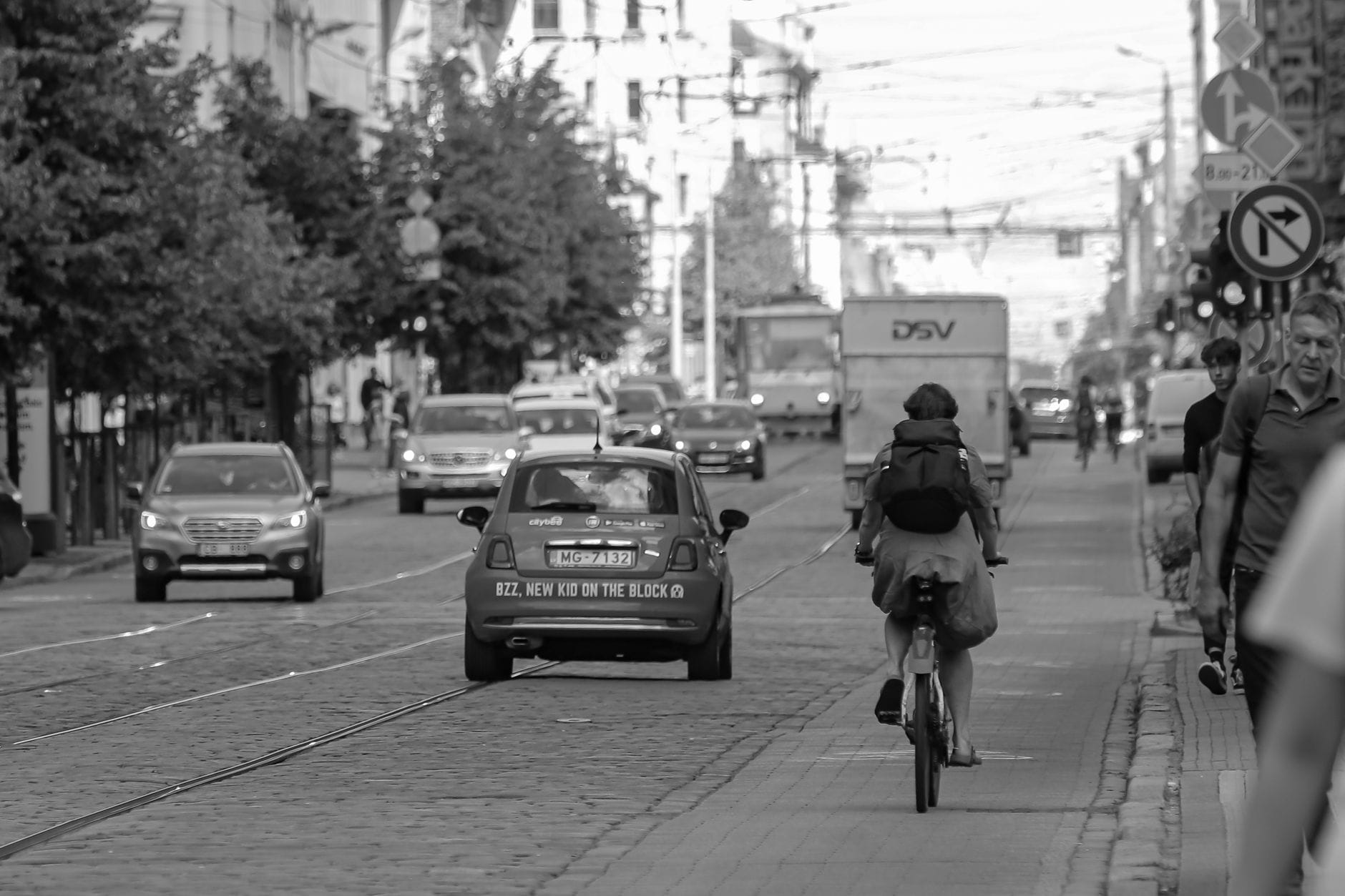Ruchliwa ulica w mieście z samochodami i pieszymi na chodniku Ruchliwa ulica w mieście z samochodami i pieszymi na chodniku