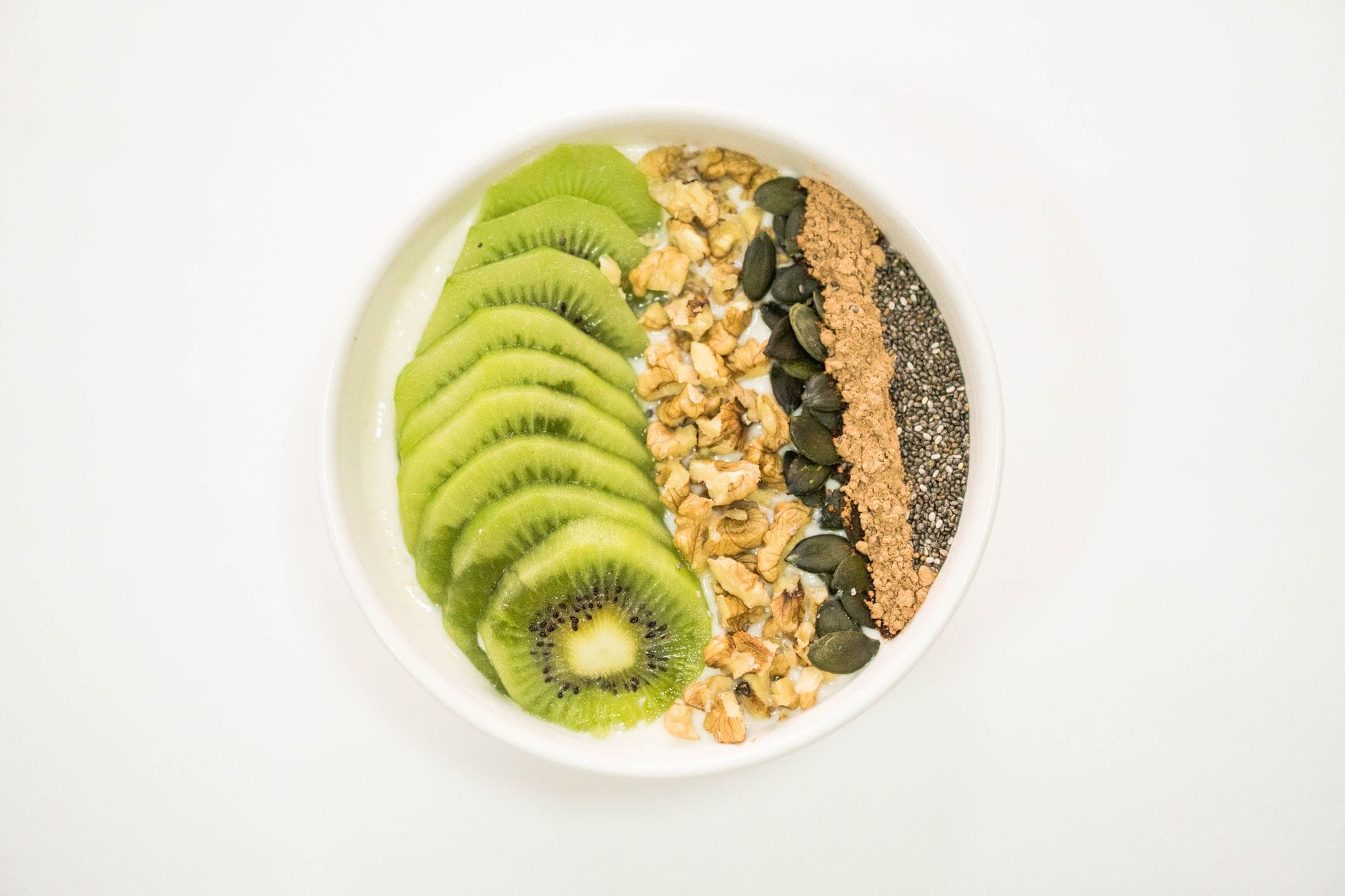 Kolorowa miska smoothie z kiwi, orzechami, nasionami i jogurtem